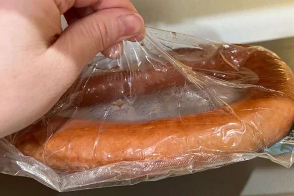 Une saucisse sous vide, maintenue par une main.