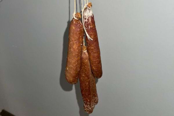 Des saucissons suspendus par des ficelles.