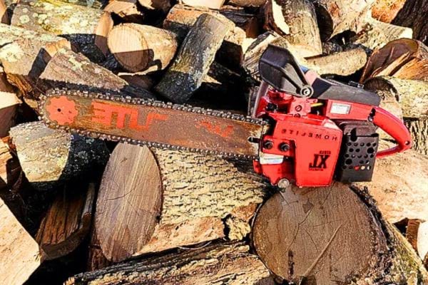 Tronçonneuse rouge reposant sur des bûches de bois.