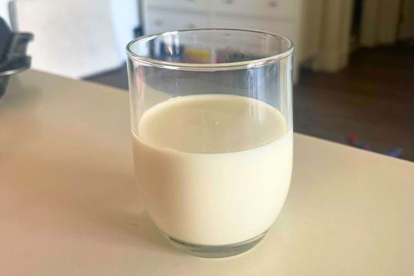 Verre de lait posé sur une table blanche.