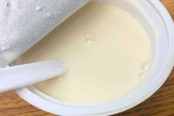 Yaourt blanc vu de dessus avec un couvercle partiellement ouvert.