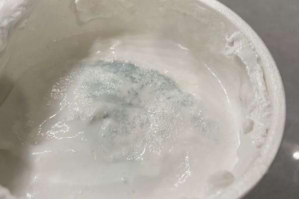 Moisissure visible sur le yaourt dans le pot.