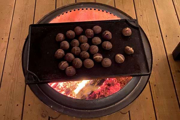 Châtaignes posées sur une plancha au-dessus d'un feu.