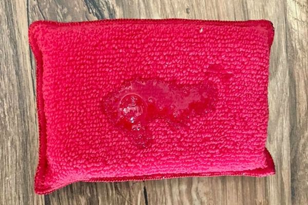 Éponge rouge absorbant un liquide.