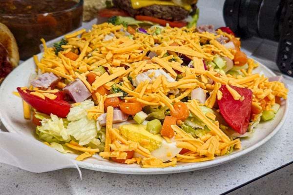 Salade garnie de légumes et fromage râpé.