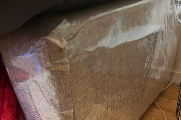 Canapé protégé par une couverture en plastique.