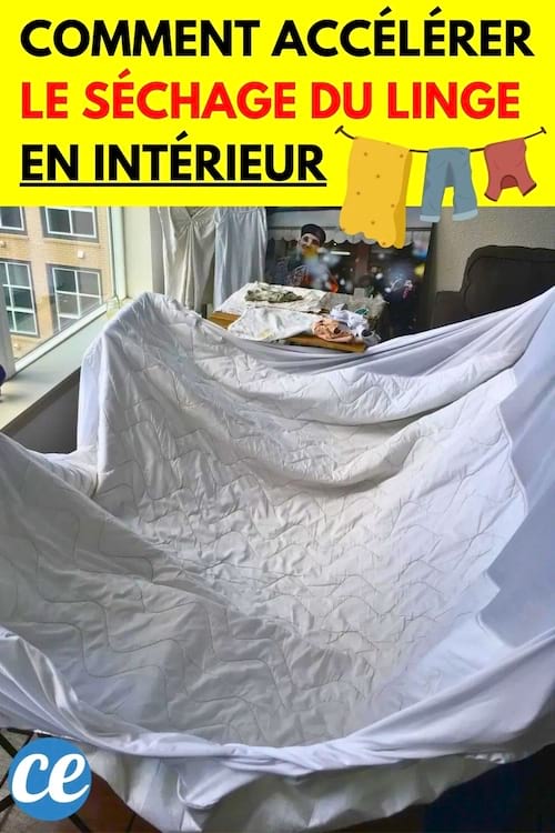 Un drap blanc sèche dans une pièce lumineuse avec du linge suspendu en arrière-plan.