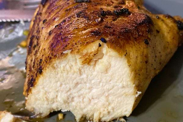 Portion de poulet grillé coupée montrant l'intérieur juteux.