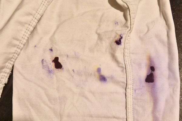 Tissu blanc taché de vernis à ongles violet et noir.