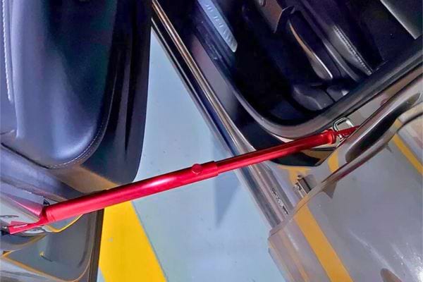 Une barre de soutien rouge est fixée au crochet de la portière pour stabiliser ou assister l'occupant du véhicule.