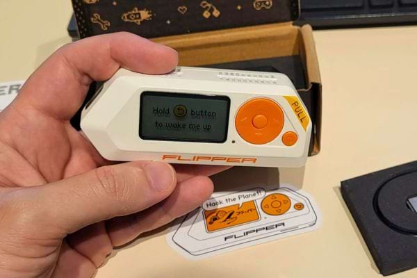 Un boîtier Flipper Zero blanc tenu dans une main, prêt à être activé.