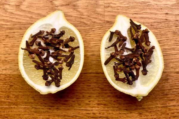 Vue rapprochée de deux moitiés de citron avec clous de girofle sur bois.