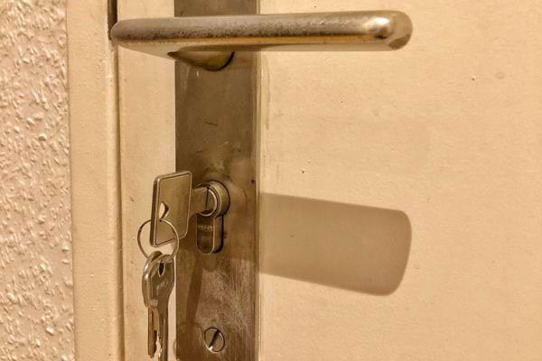 Clés pendantes dans la serrure d'une porte avec poignée en métal.