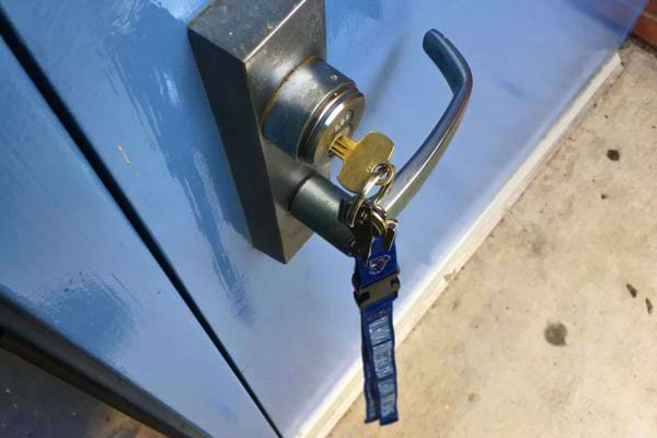 Clé avec étiquette bleue insérée dans la serrure d'une porte bleue.