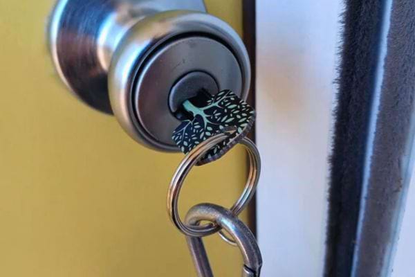 Clé insérée dans la serrure d'une porte, détail sur un porte-clés décoratif.