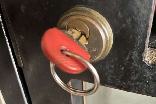 Clé avec lanière rouge dans la serrure d'une porte noire.