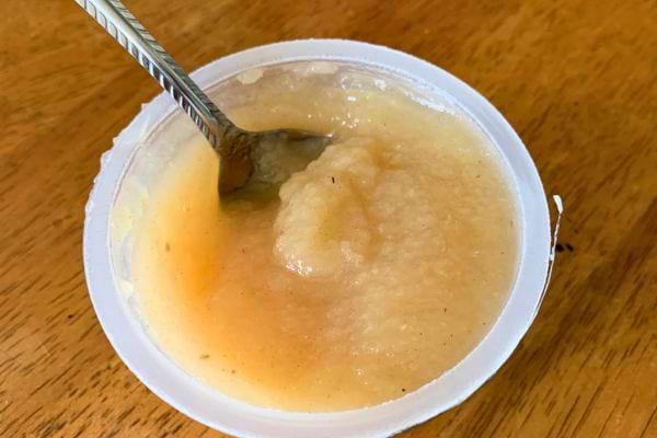 Compote de pomme dans un pot ouvert avec une cuillère.