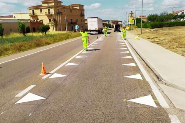 Des gens qui peignent la route pour y mettre des dents du dragon