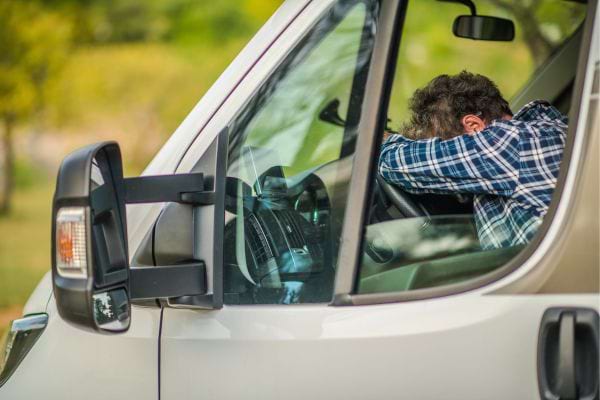 Un conducteur épuisé se repose sur le volant.
