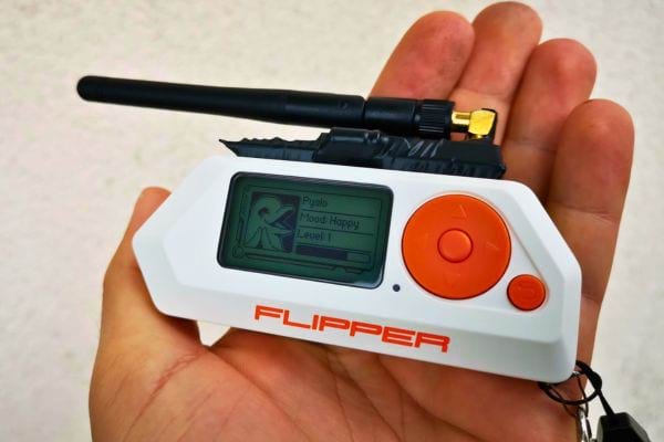 Flipper Zero avec une antenne déployée, affichant un écran "Happy".