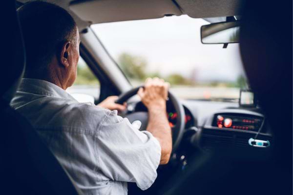Un homme âgé conduisant une voiture.