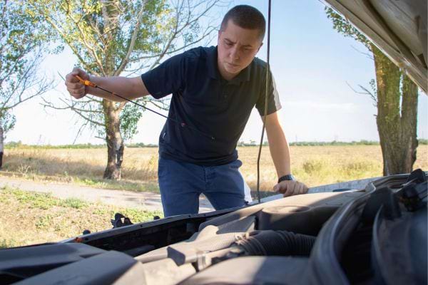 Homme vérifiant le niveau d'huile du moteur.