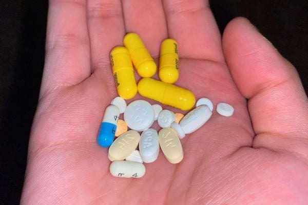 Main tenant divers comprimés et capsules de médicaments.