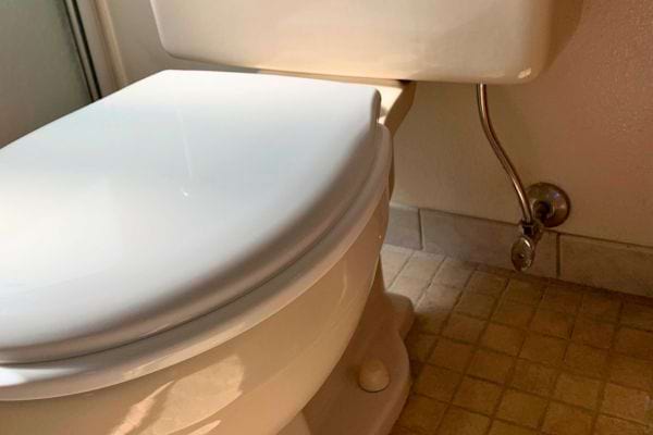 Toilette blanche près d'un mur beige avec carrelage marron.