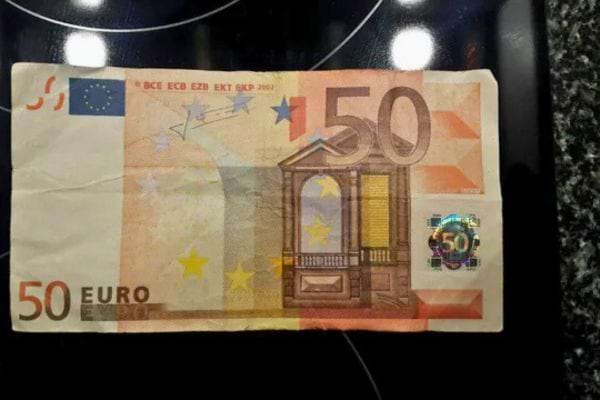 Billet de cinquante euros posé sur une surface noire.