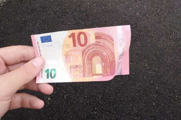 Billet de dix euros froissé dans une main.