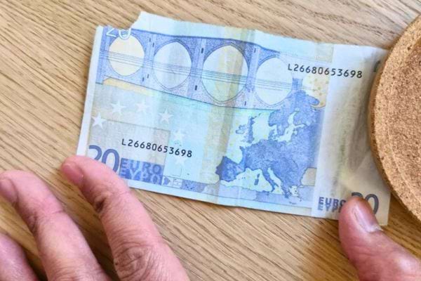 Main tenant un billet de vingt euros.