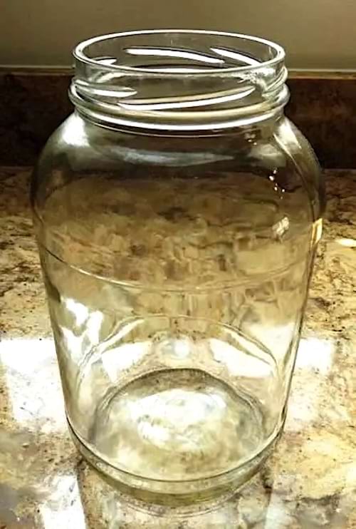 Un grand bocal en verre sur un plan de travail en pierre naturelle.