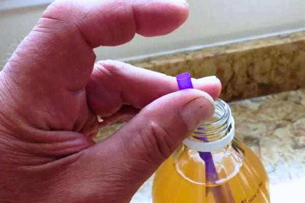 Un doigt relâché sur une paille pour extraire de la mère de vinaigre.