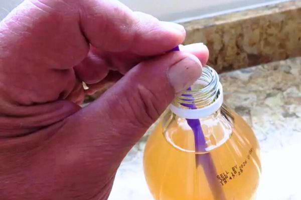 Un doigt à l'extrémité d'une paille pour retirer la mère de vinaigre d'une bouteille.