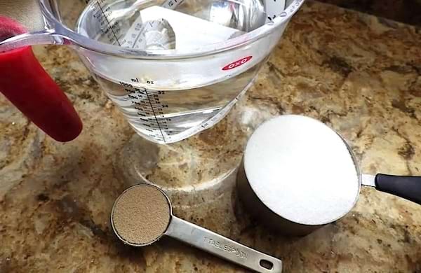 Du sucre, de la levure boulangère, et un broc verseur avec de l'eau.