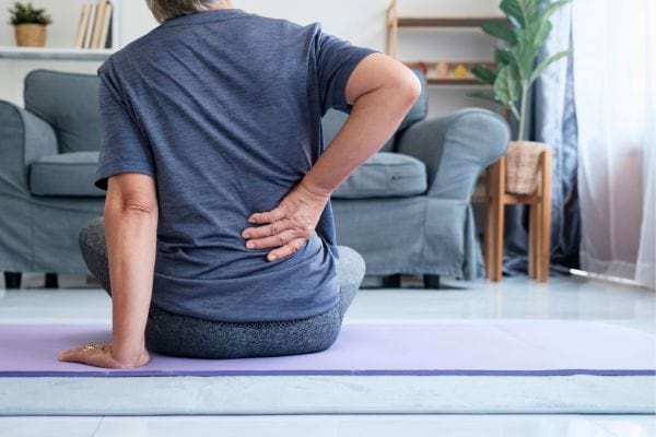 Un homme assis touchant son dos, exprimant une gêne.