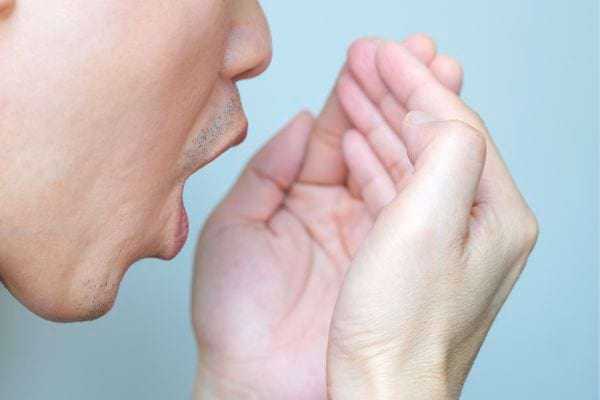 Homme vérifiant son haleine.