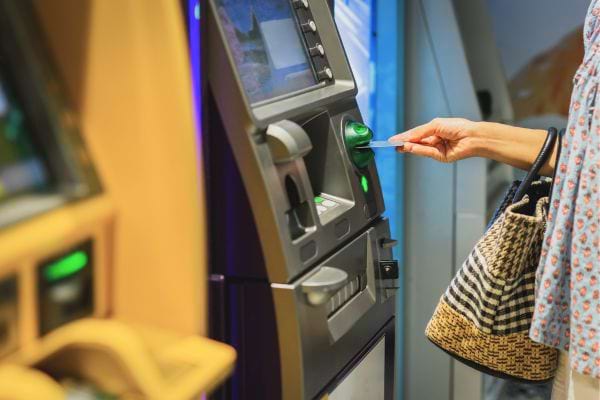 Femme insérant une carte dans un distributeur.