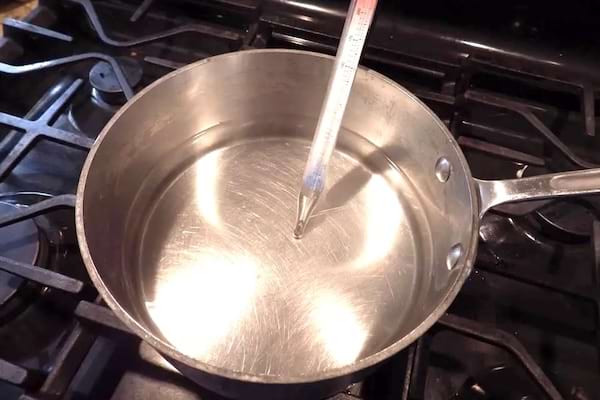 Un thermomètre à bonbons dans une casserole d'eau chaude.