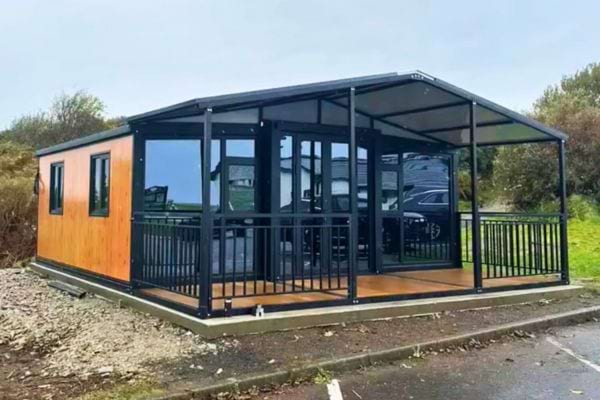 Tiny house avec terrasse couverte et structure métallique.