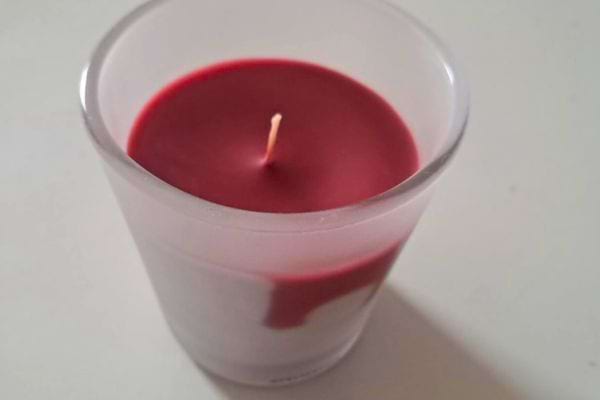 Bougie rouge allumée sur une surface claire.