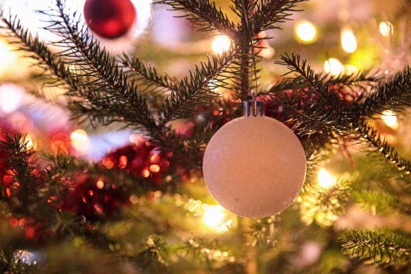 Une boule de Noël blanche accrochée à un sapin lumineux.