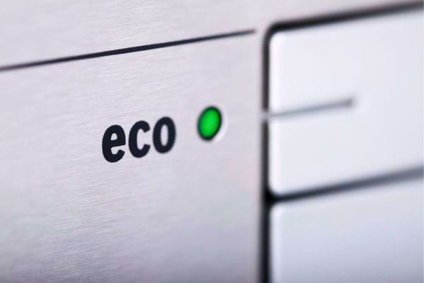 Gros plan sur un bouton "eco" avec voyant vert sur un appareil.
