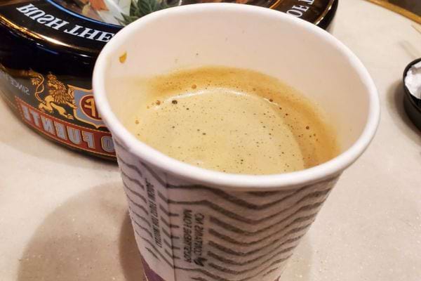 Gobelet de café sur une table, près d'une cuillère.