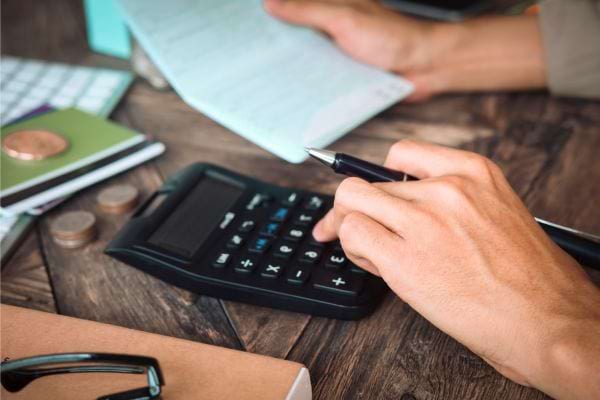 Personne utilisant une calculatrice sur des documents.