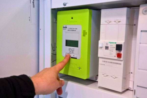 Une main appuie sur un compteur Linky.