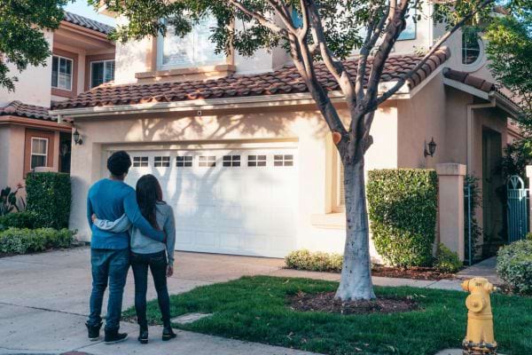Couple de dos admirant leur maison avec garage.
