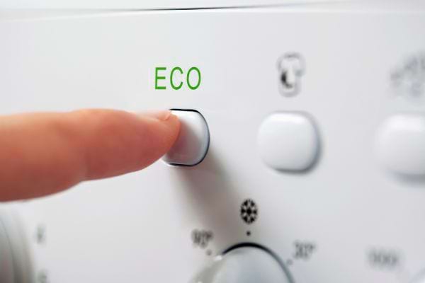 Doigt appuyant sur un bouton "eco" d'un appareil ménager.