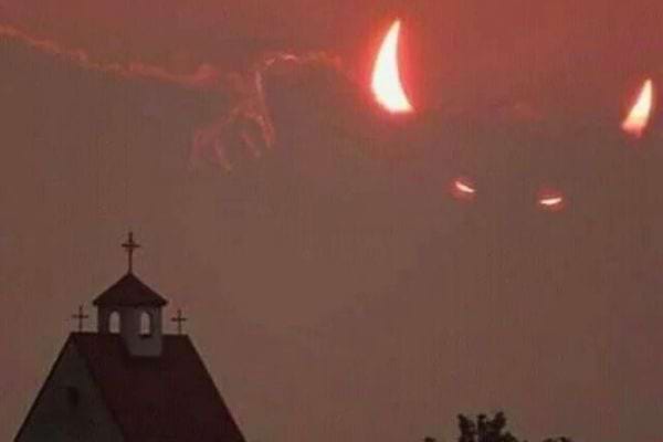 Éclipse avec des "cornes" illuminant le ciel derrière un clocher d'église.