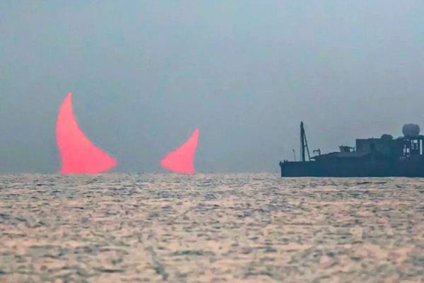 Deux formes lumineuses évoquant des cornes au-dessus d'un navire en mer.